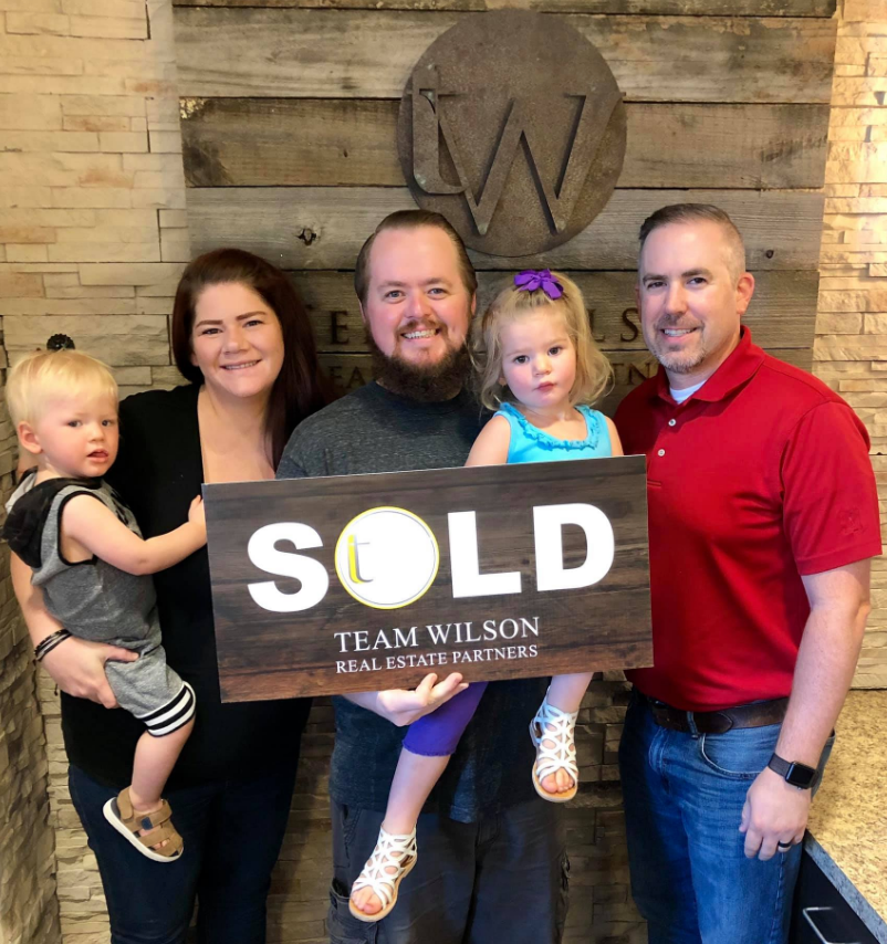 Real estate agent and clients holding