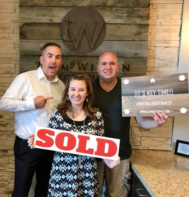 Real estate agent and clients holding