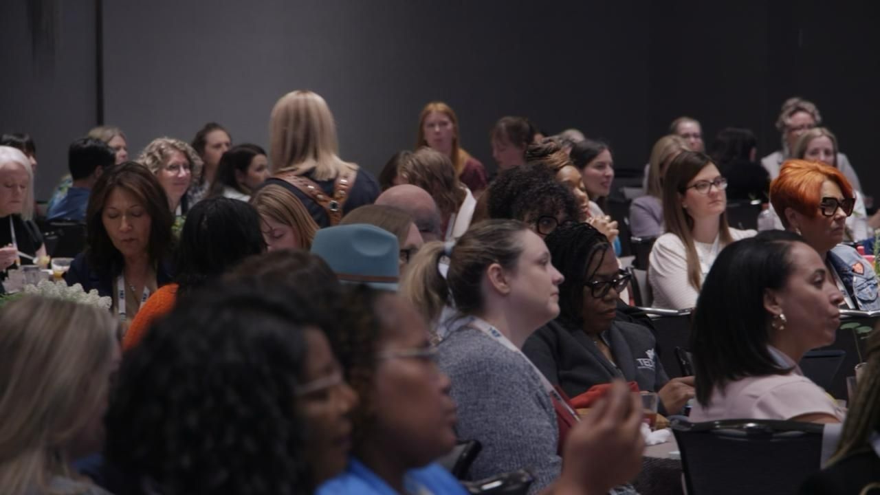 Audience in a conference room; people listen to a presentation.