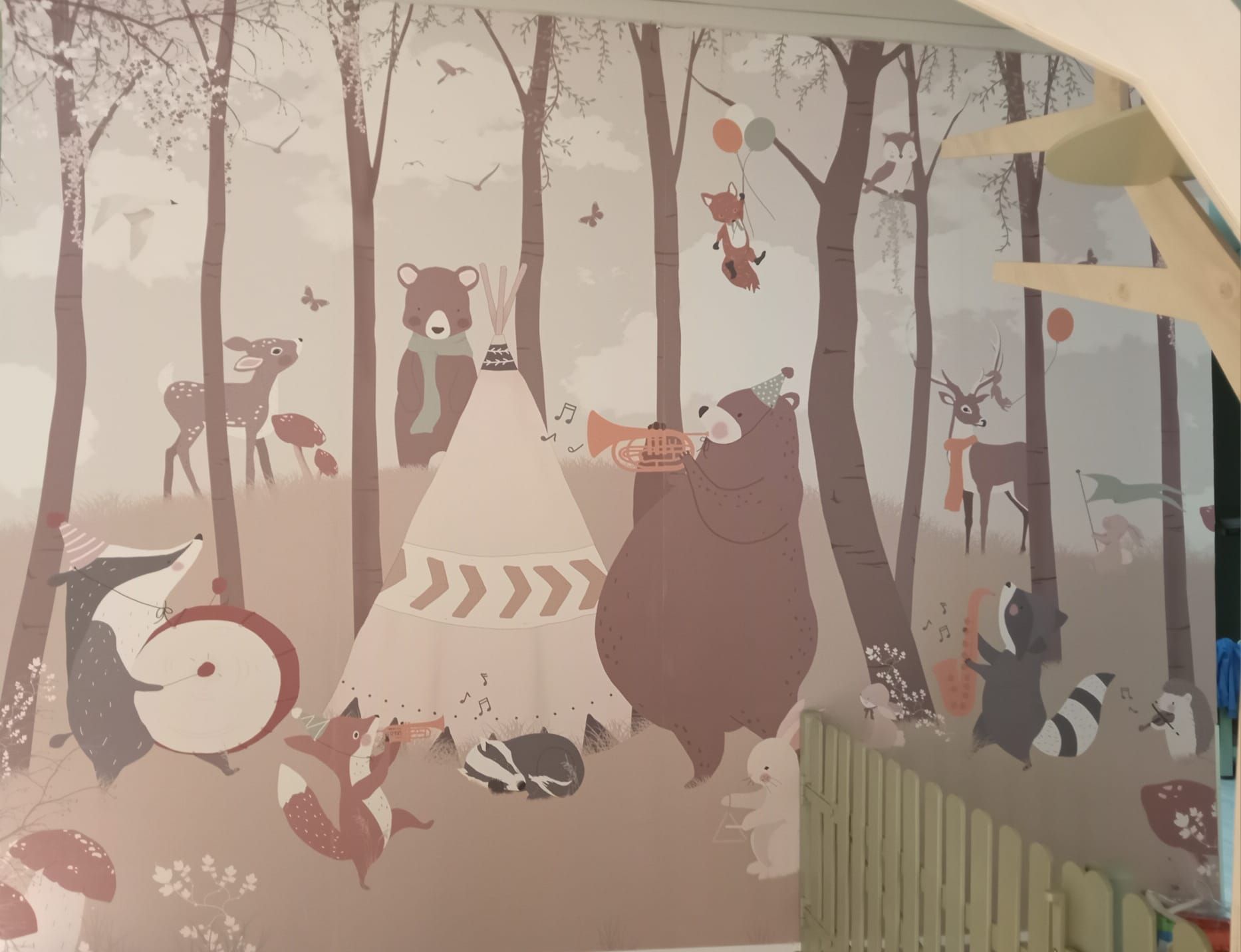 Un murales ispirato al bosco con animali dei cartoni animati. Un orso suona la tromba vicino a una tenda indiana.