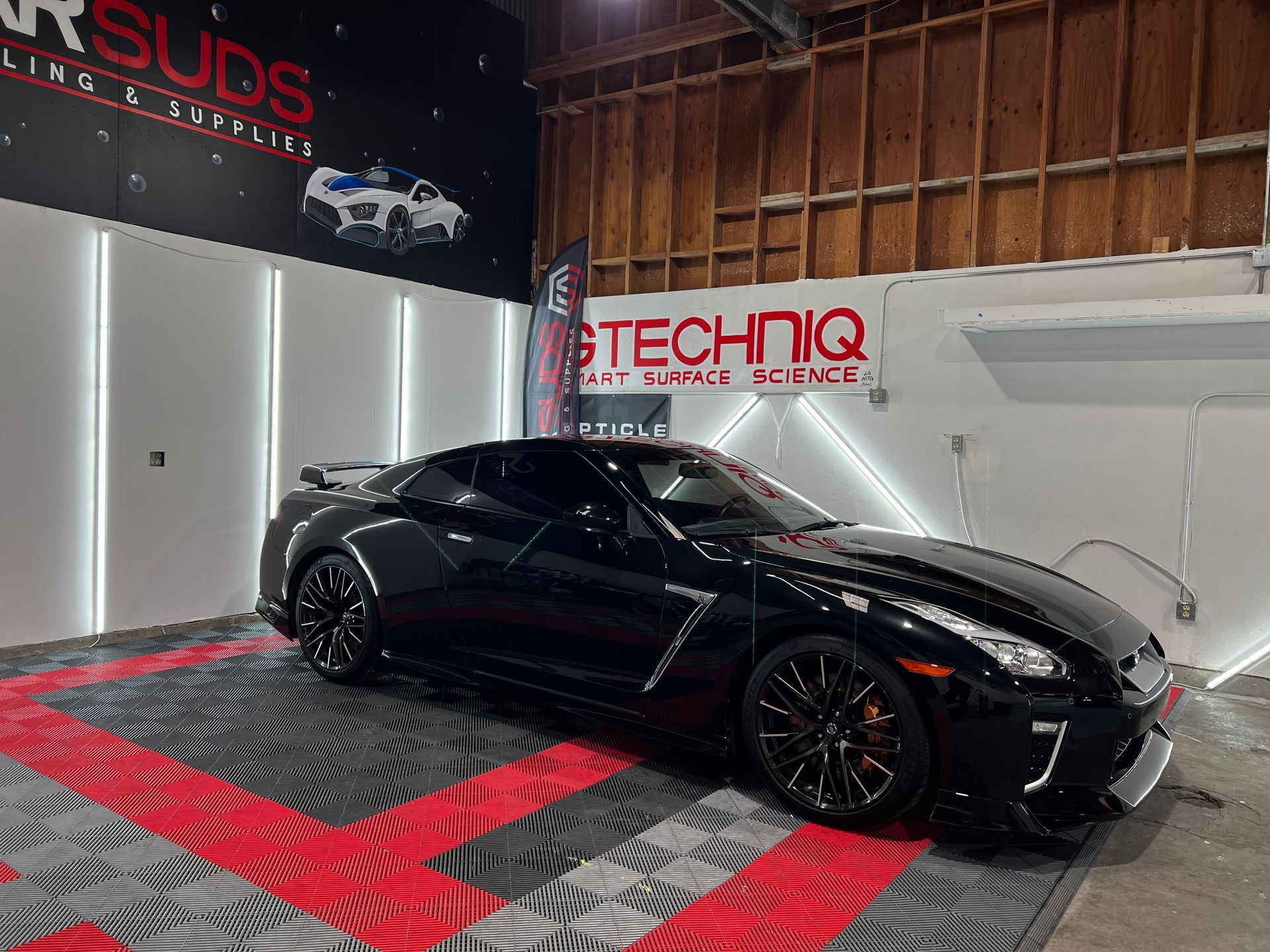 A black sports car is parked in a garage.
