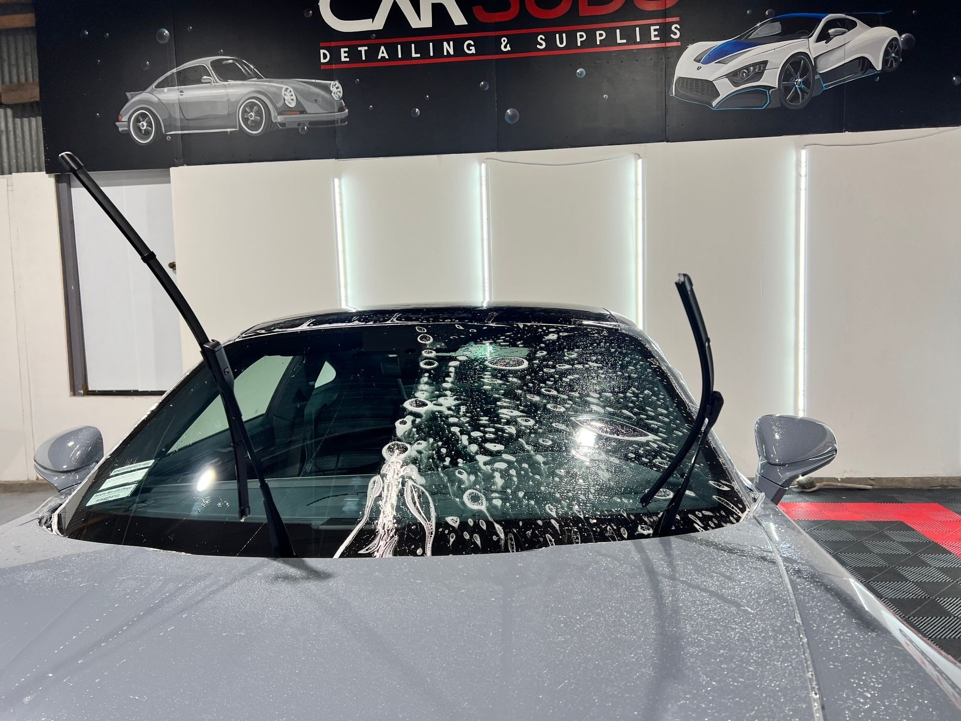 A car with a broken windshield is parked in front of a car wash.