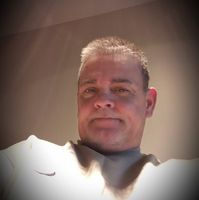 A man wearing a white nike shirt looks at the camera