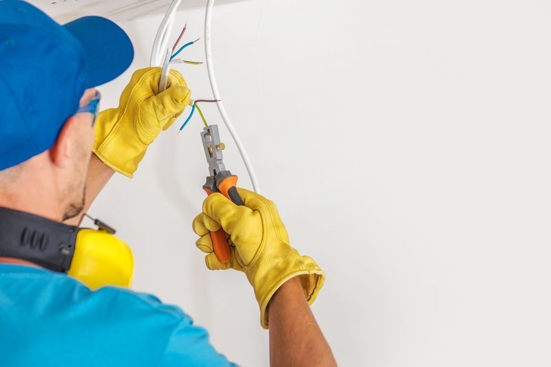 A man is cutting a wire with a pair of pliers.