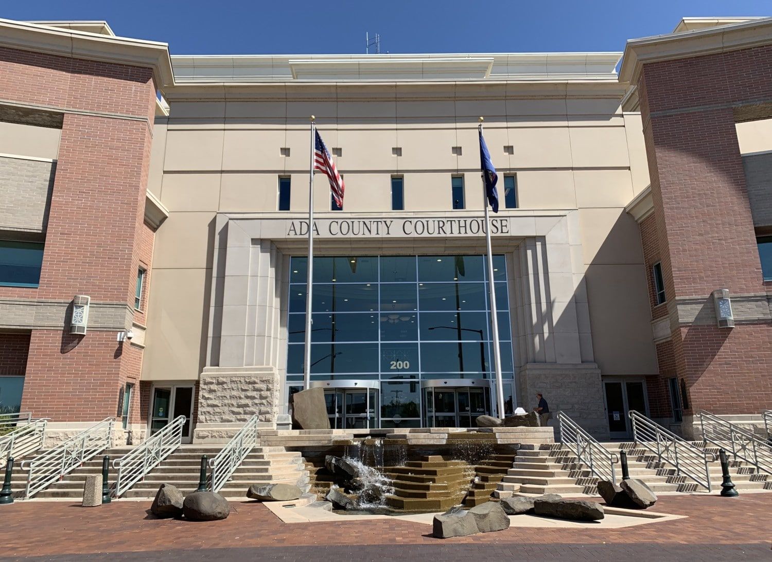 The front of a large building with stairs and flags.