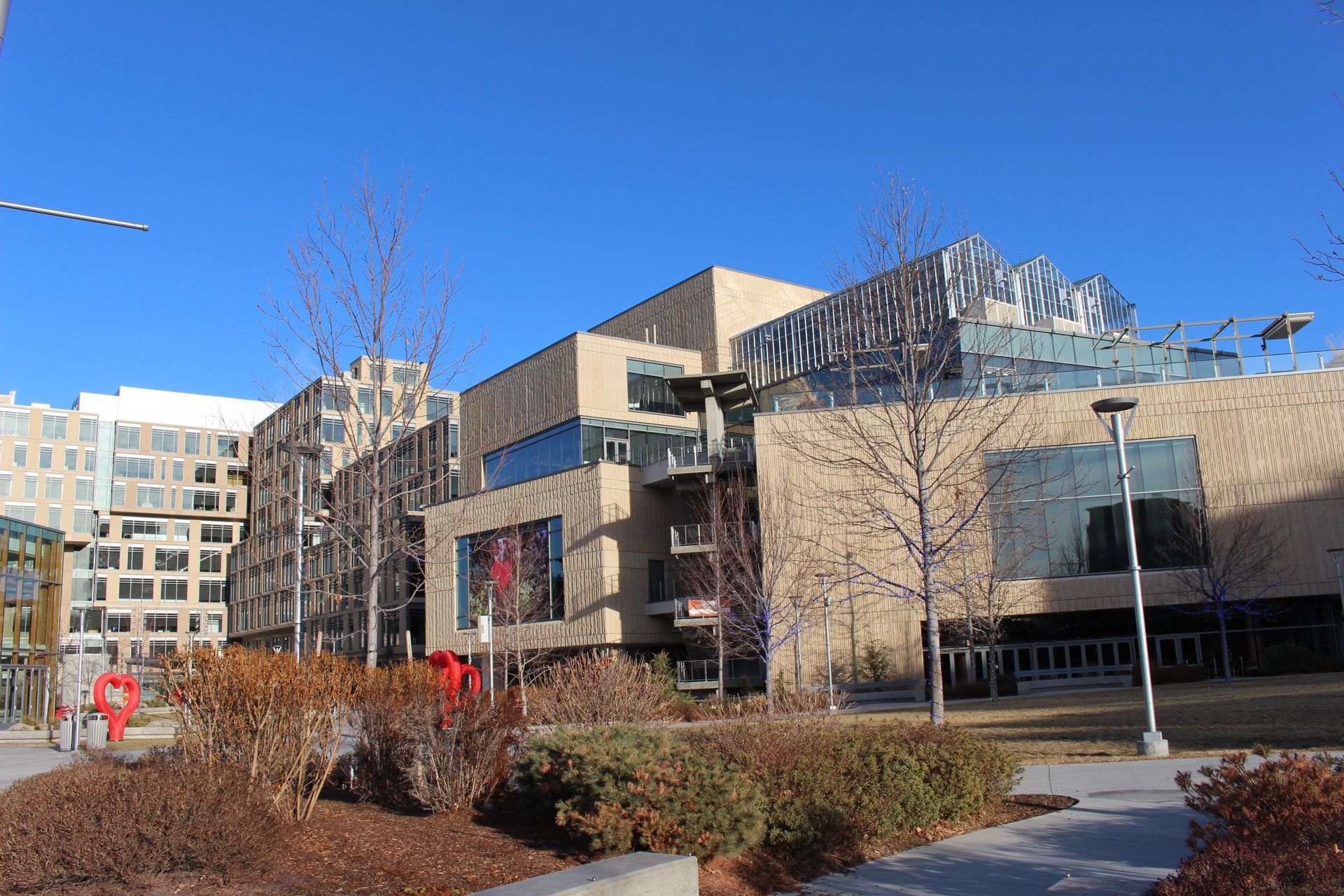 A large building with a lot of windows is surrounded by trees and bushes.