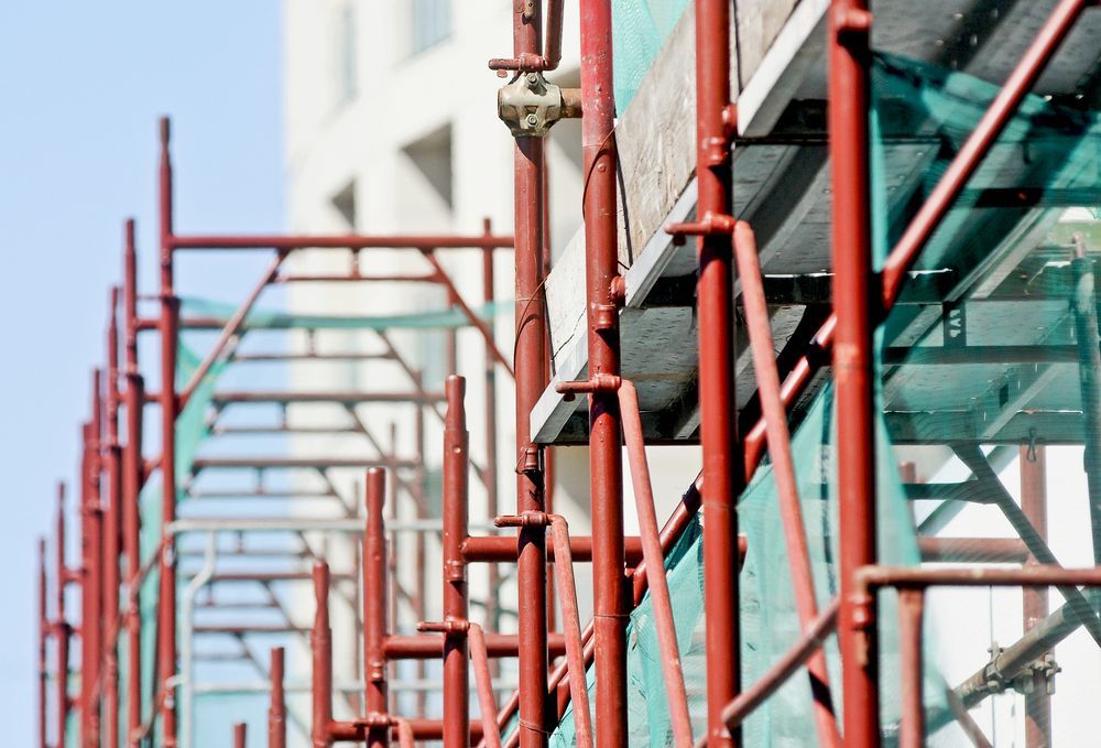 Red Scaffolding on a Building Under Construction With Green Safety Netting — NRS Scaffolding Pty Ltd in Taree, NSW