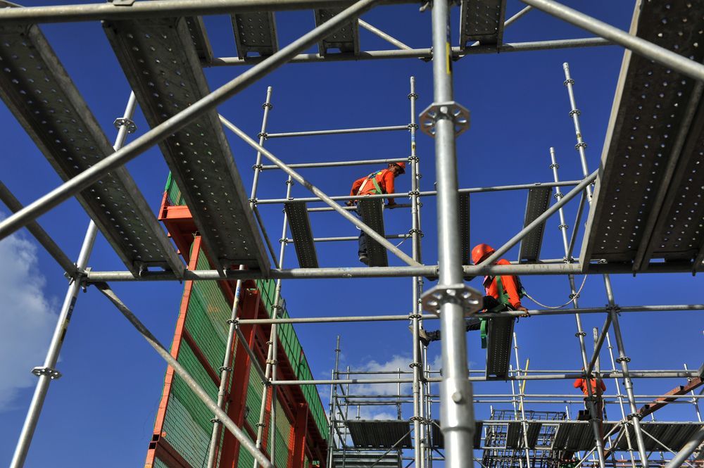 Workers in Orange Vests on Scaffolding Against a Blue Sky — NRS Scaffolding Pty Ltd in Wingham, NSW