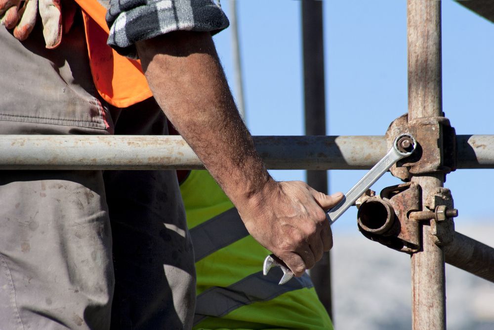 Construction Worker Tightening a Bolt on Scaffolding With a Wrench, Outdoors — NRS Scaffolding Pty Ltd in Forster, NSW