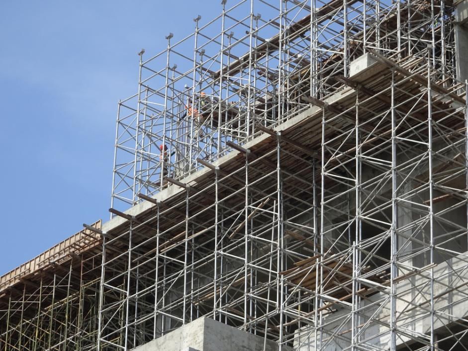 Scaffolding Surrounds a Building Under Construction Against a Clear Blue Sky — NRS Scaffolding Pty Ltd in Nambucca Heads, NSW