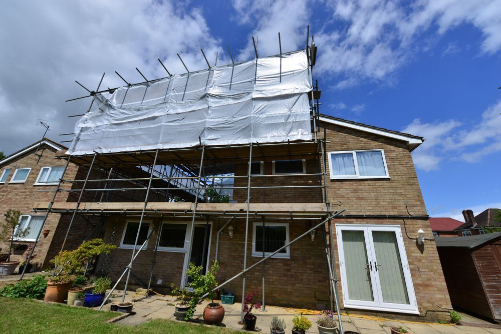 House With Scaffolding and Protective Sheeting Under a Bright Blue Sky — NRS Scaffolding Pty Ltd in Wingham, NSW