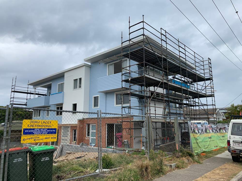 Building Under Construction With Scaffolding, Blue Siding, Brick Base — NRS Scaffolding Pty Ltd in Port Macquarie, NSW