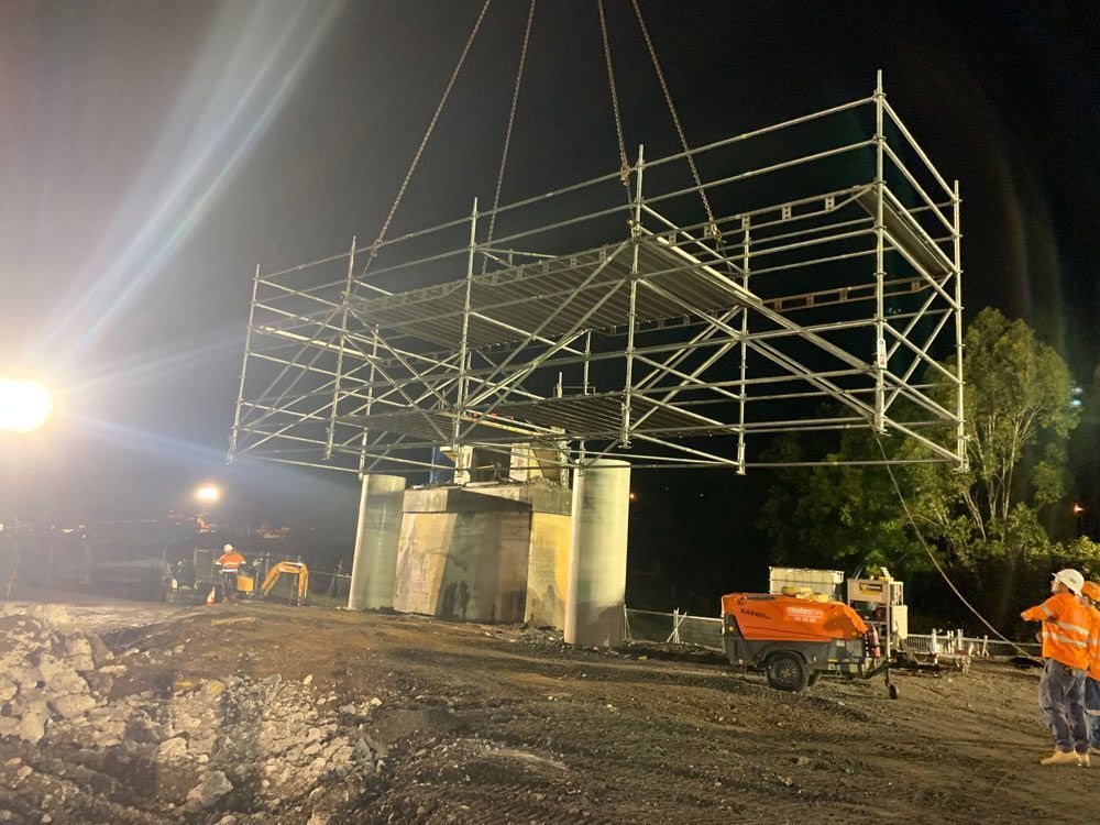 Scaffolding Being Lowered Onto Concrete Pillars at Night by a Crane Workers — NRS Scaffolding Pty Ltd in Wauchope, NSW
