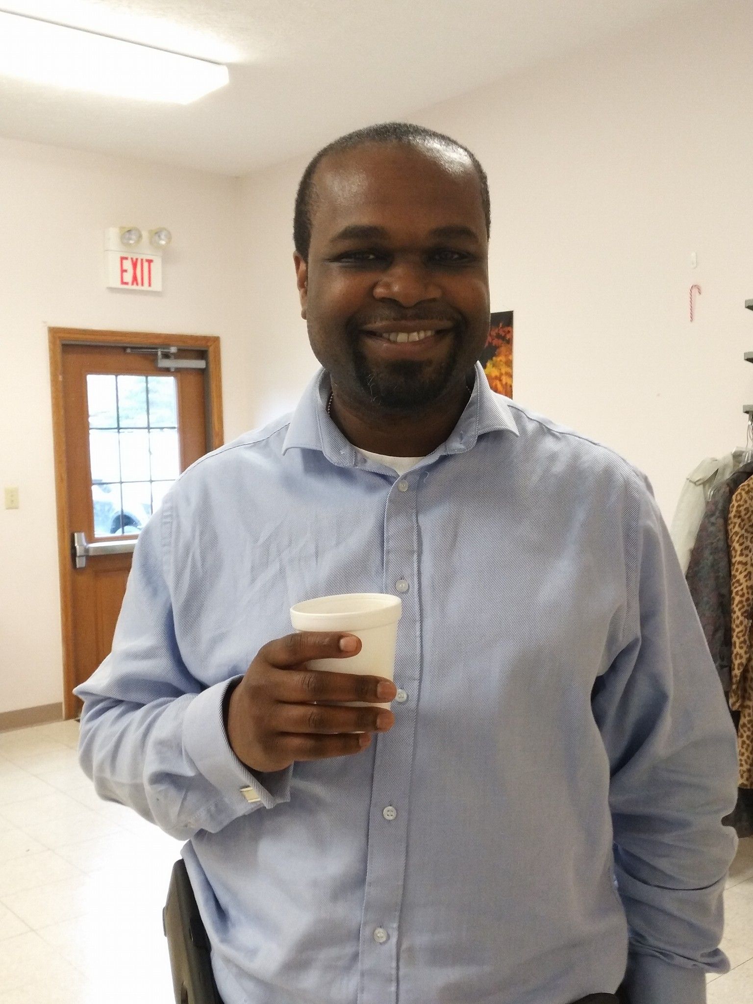 A man in a blue shirt is holding a cup of coffee.