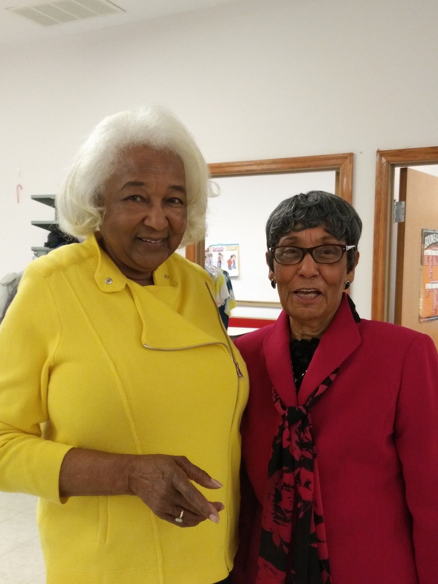Two women are posing for a picture and one is wearing a yellow jacket