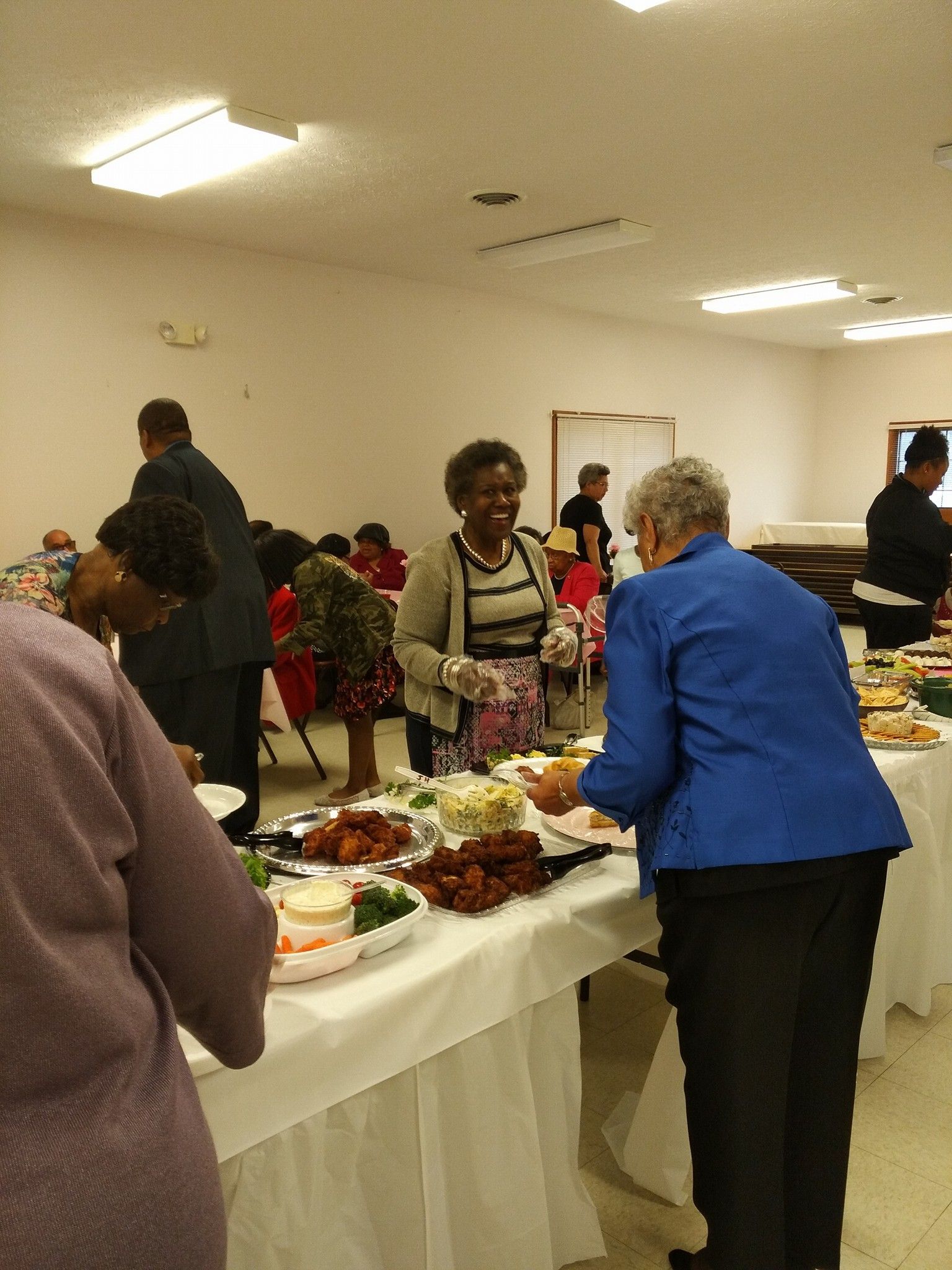 A woman in a blue jacket is standing at a buffet table