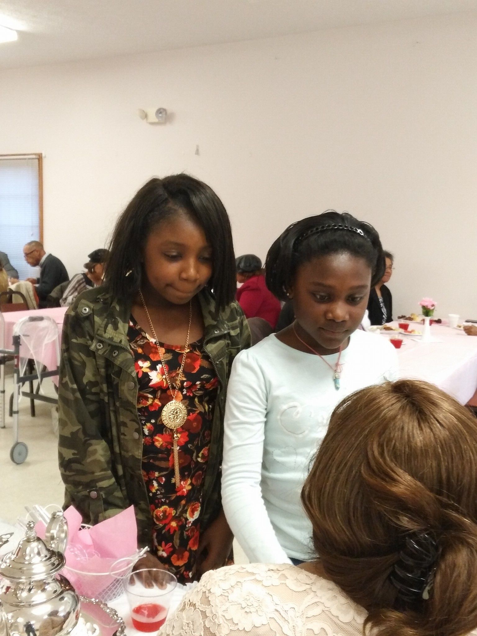 Two young girls are standing next to each other in a room.