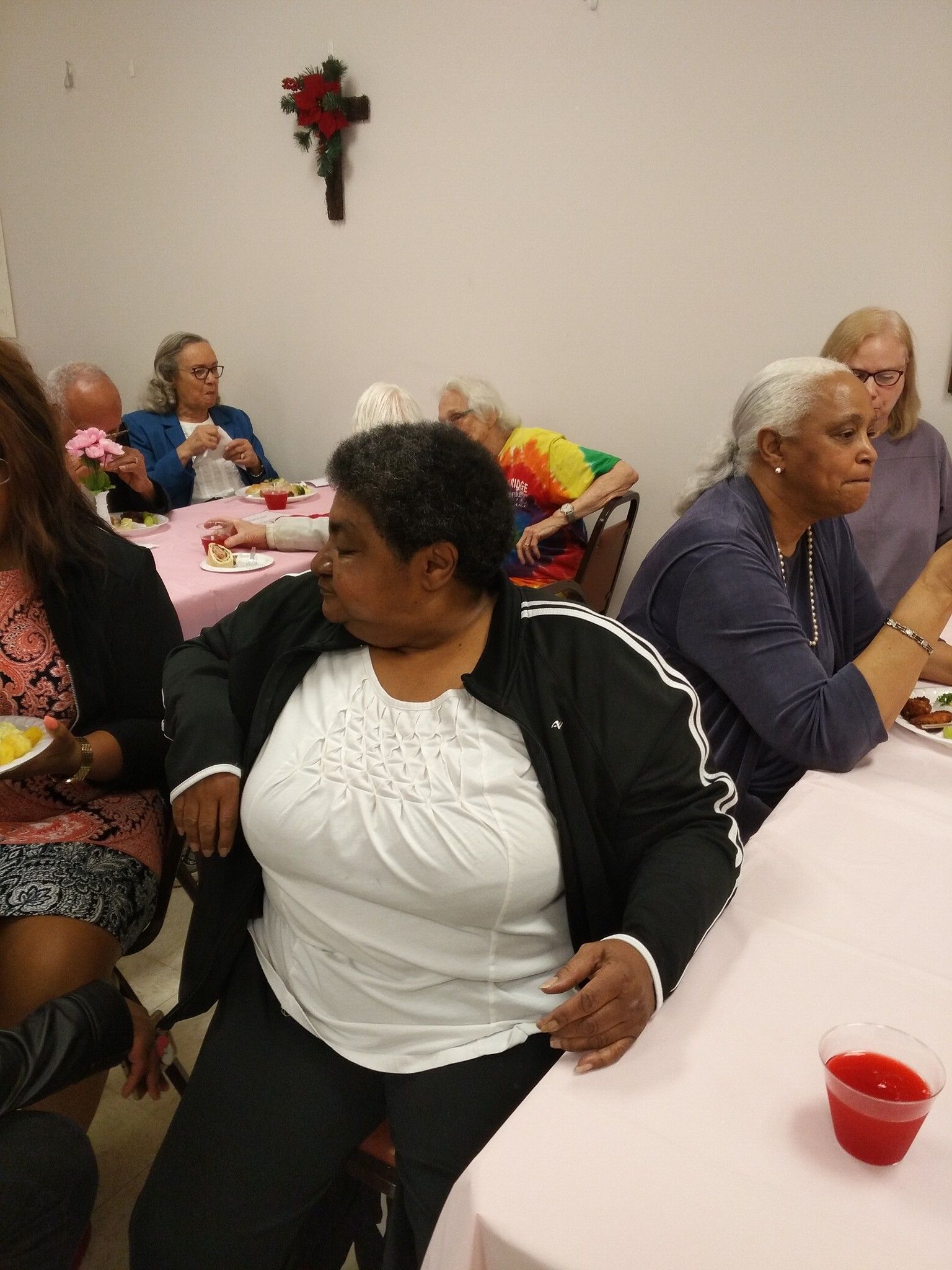 A group of women are sitting at tables with plates of food.