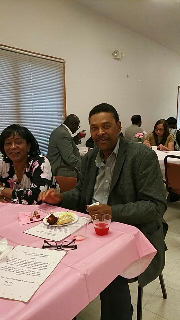 A man and a woman are sitting at a table with pink table cloths.