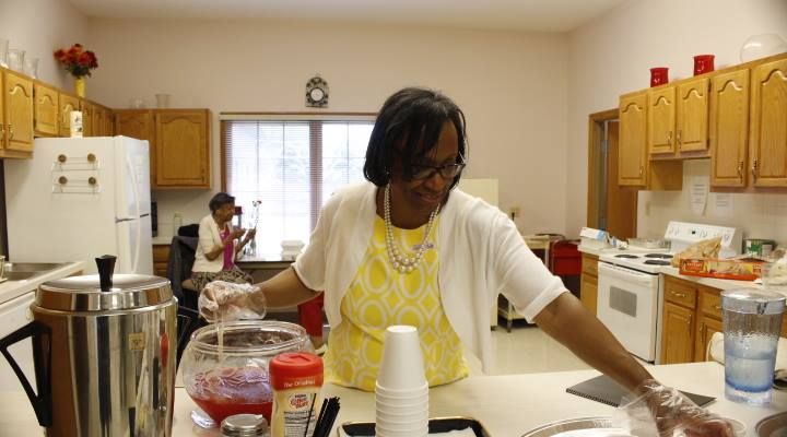 A woman is standing in a kitchen preparing food.