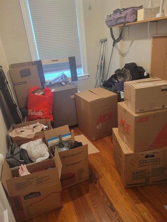 A room filled with lots of cardboard boxes and a window.
