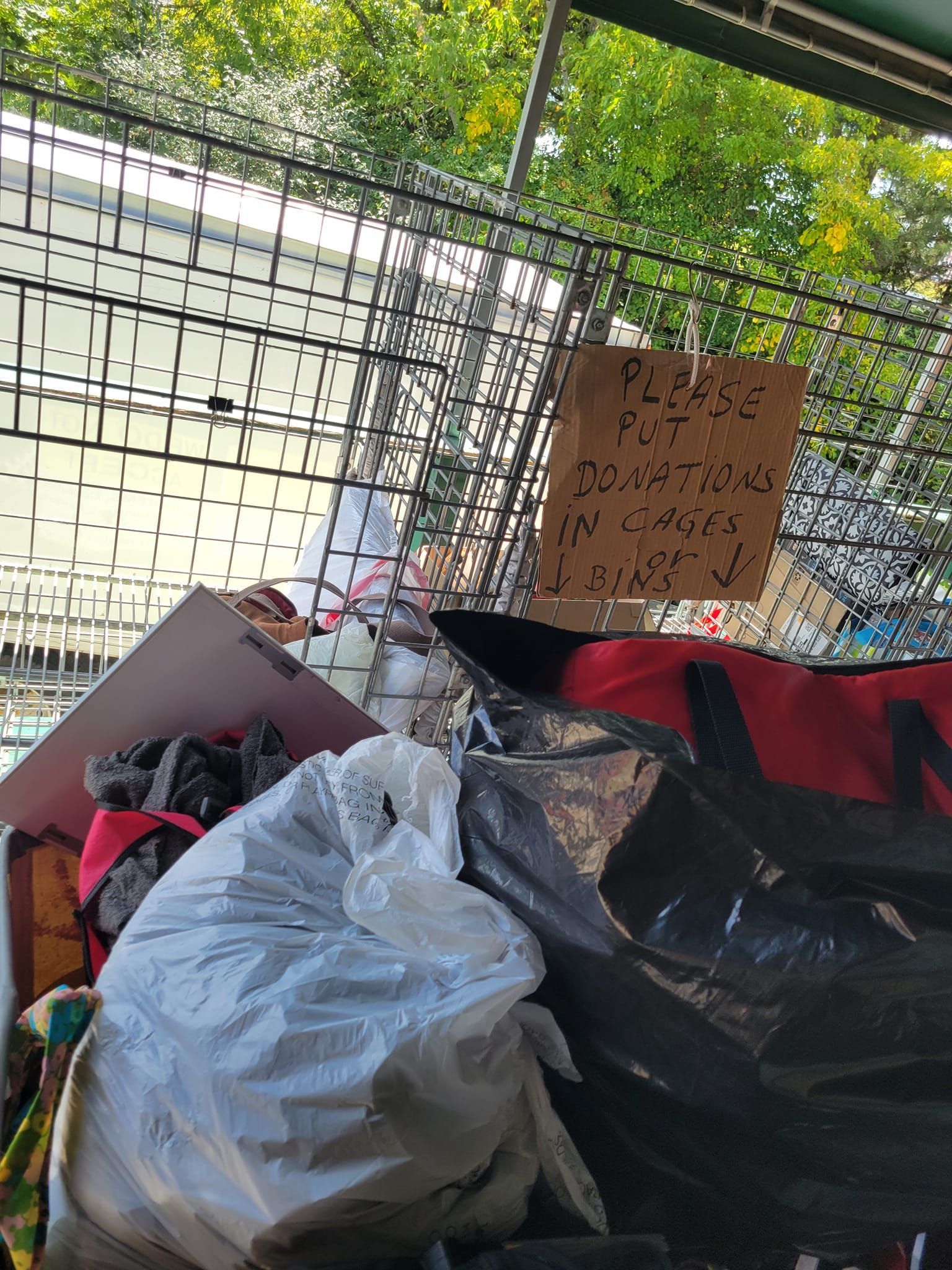 A pile of trash with a sign that says please put donations in bags