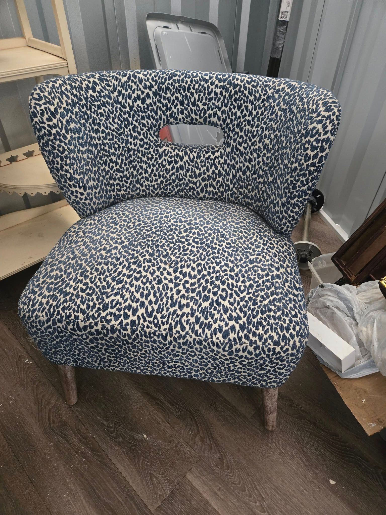 A black and white chair with a hole in the back is sitting on a wooden floor.