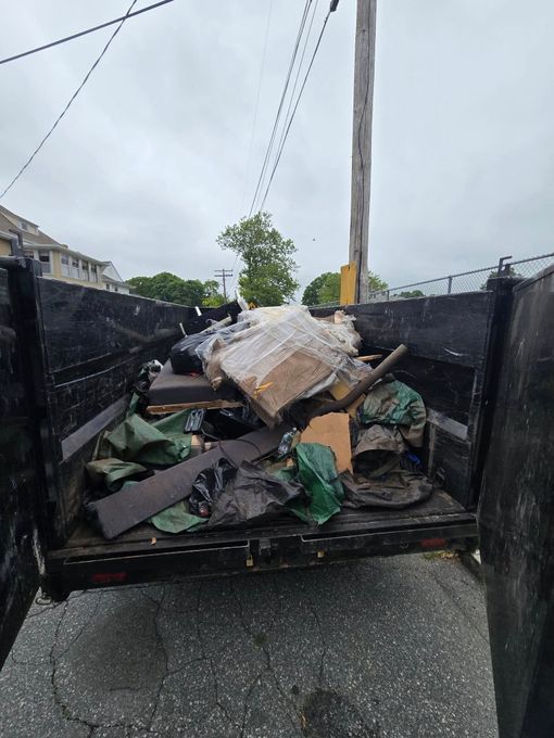 A dumpster filled with lots of trash is parked on the side of the road.