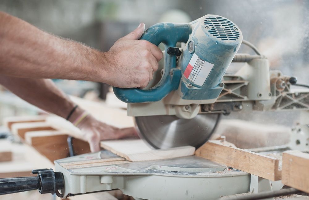 A Man Is Cutting A Piece Of Wood With A Circular Saw — Machin's Sawmill Pty Ltd In Wingham, NSW