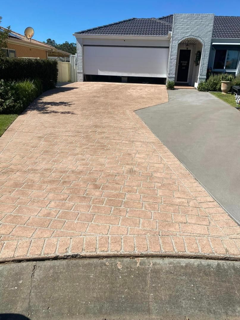 Brick Driveway Leading to a House With a Garage Door — BJ's Concreting in Huskisson, NSW