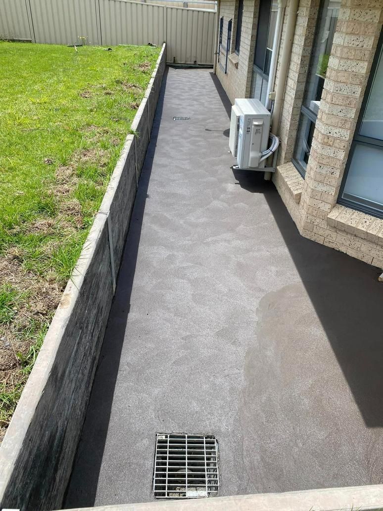 Walkway Leading to a House With a Drain on the Side of It — BJ's Concreting in Huskisson, NSW