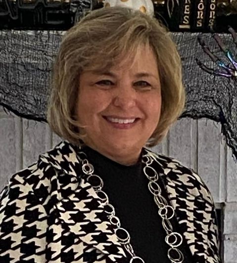 A woman is wearing a black and white jacket and smiling.