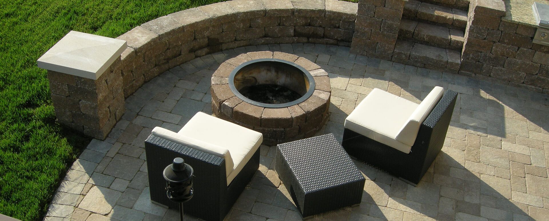 Outdoor patio with fire pit, seating, and stone walls.