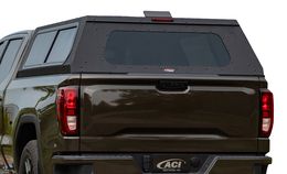 Black truck bed cap on a brown truck, rear view, with a large rear window and taillights.
