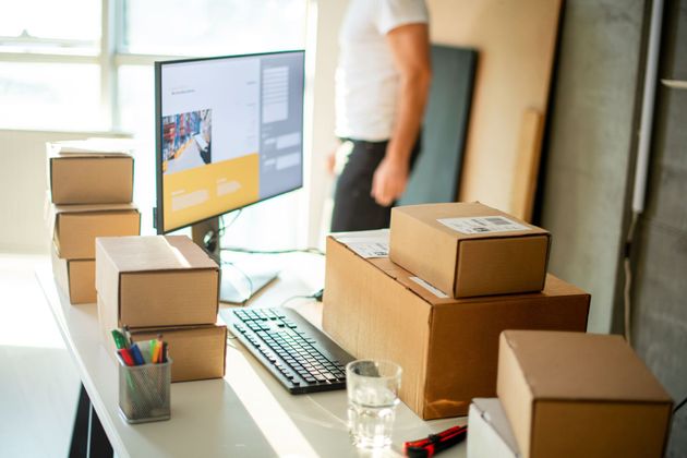 Packing boxes on an office desk beside a computer and keyboard, with a person in the background