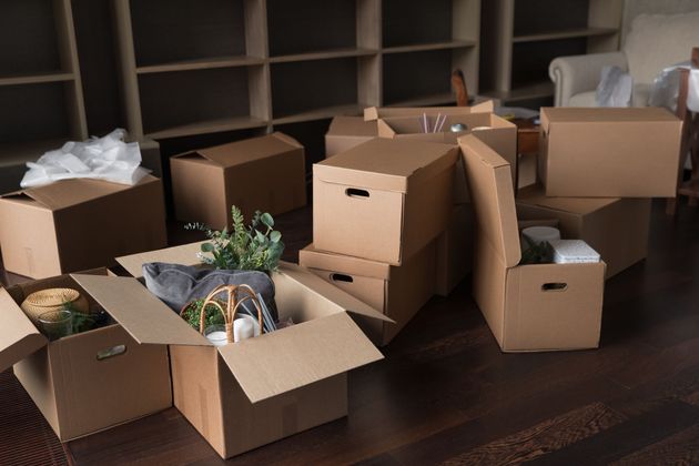 Open cardboard boxes and packing supplies scattered across a room floor.