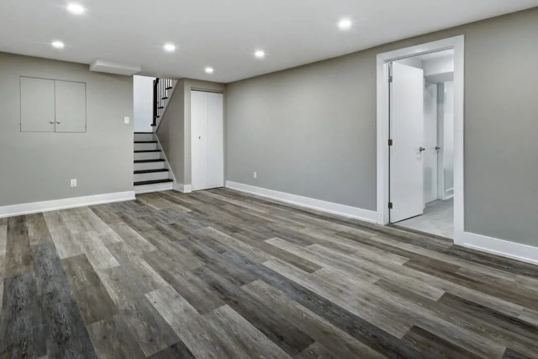 An empty basement with hardwood floors and stairs.