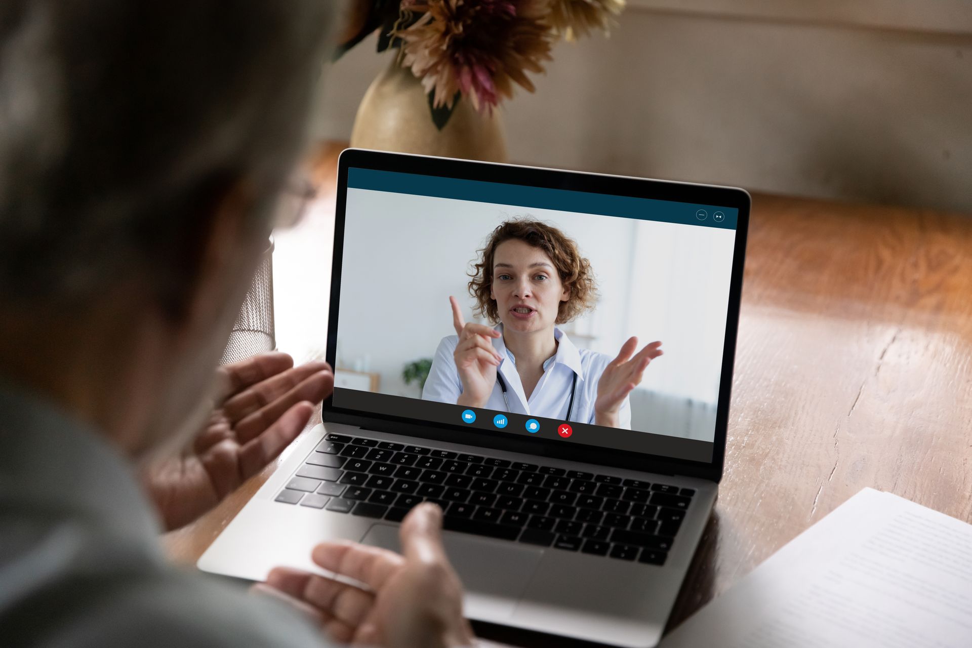An elderly man at home during a telehealth appointment with a female doctor on his laptop.