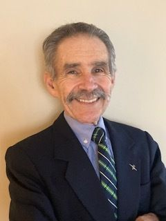 A man with a mustache and glasses is wearing a suit and tie.