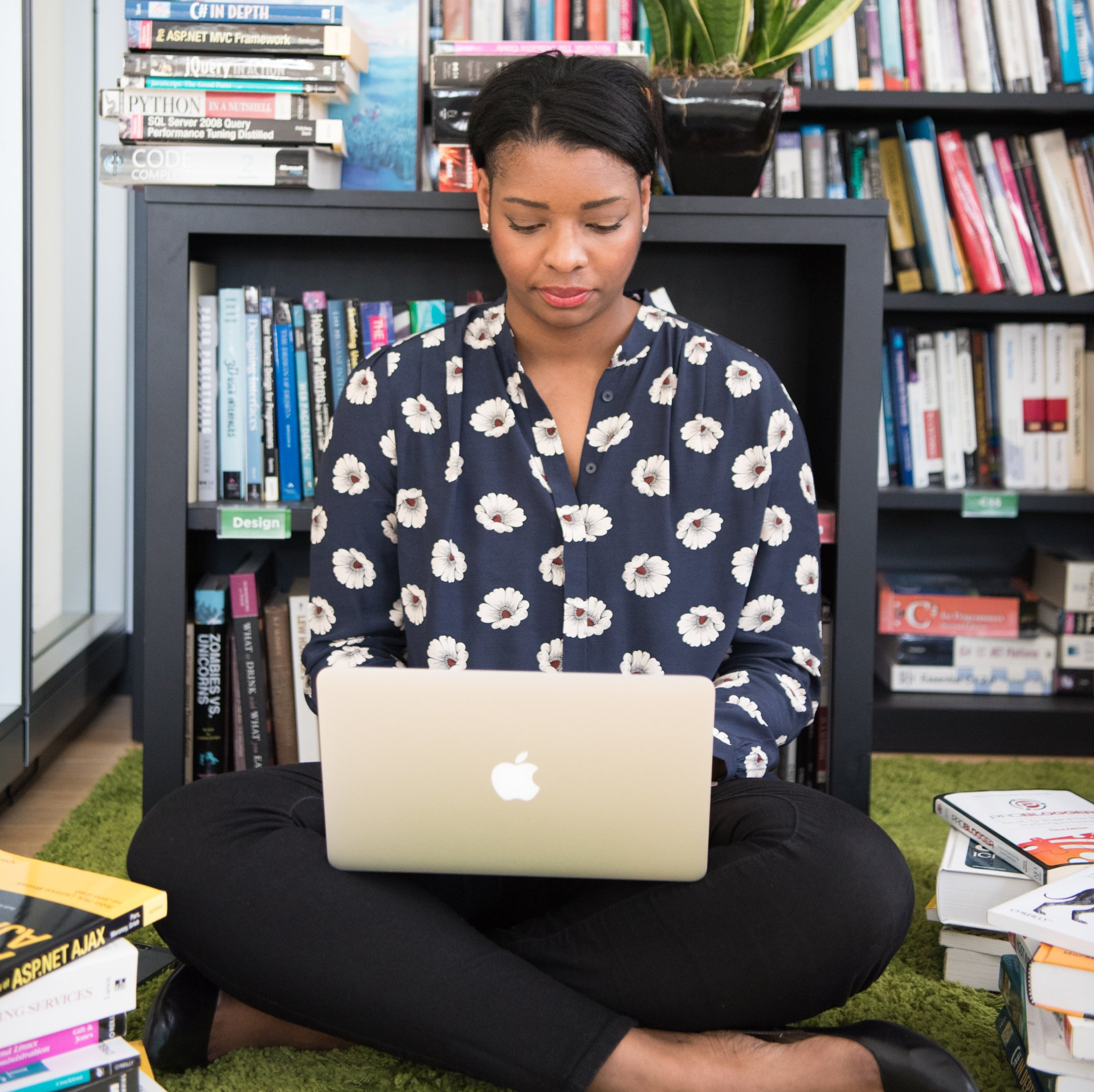 A woman is sitting on the floor using an apple laptop