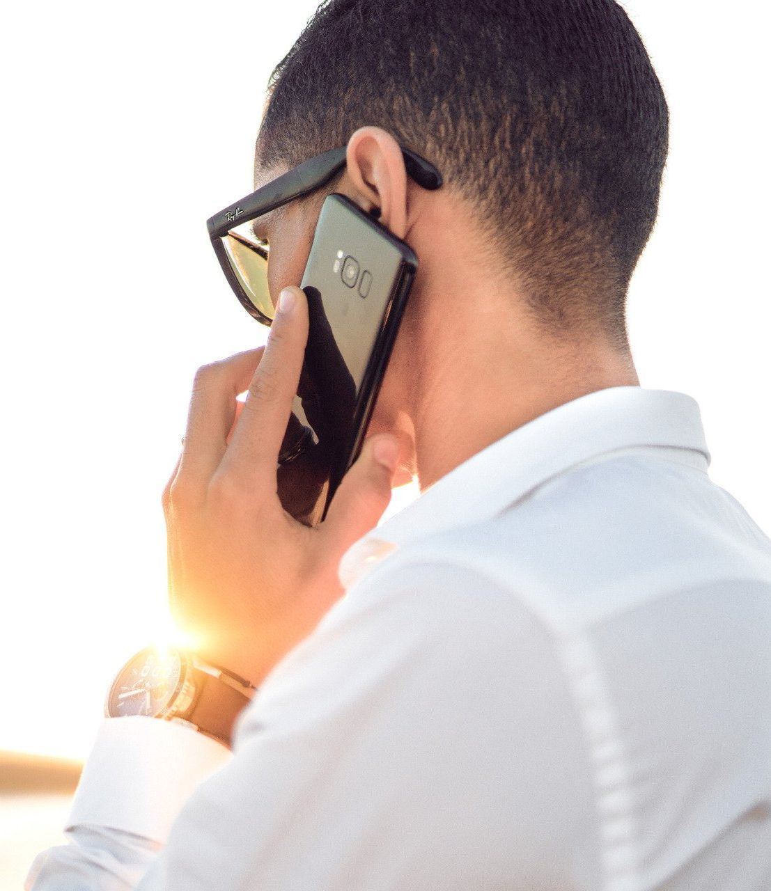 A man wearing sunglasses is talking on a cell phone