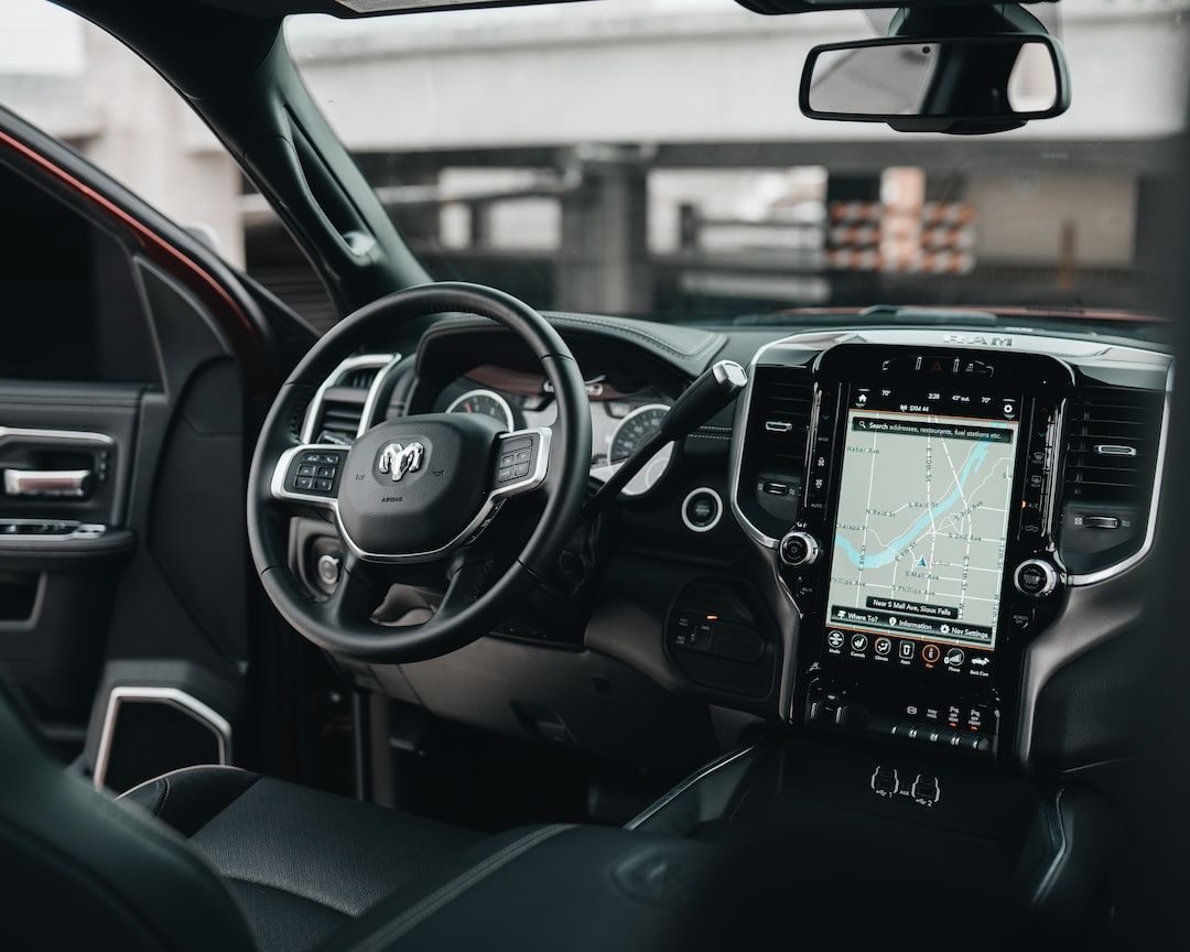 The interior of a RAM truck featuring a large portrait-oriented touchscreen display and a leather steering wheel.