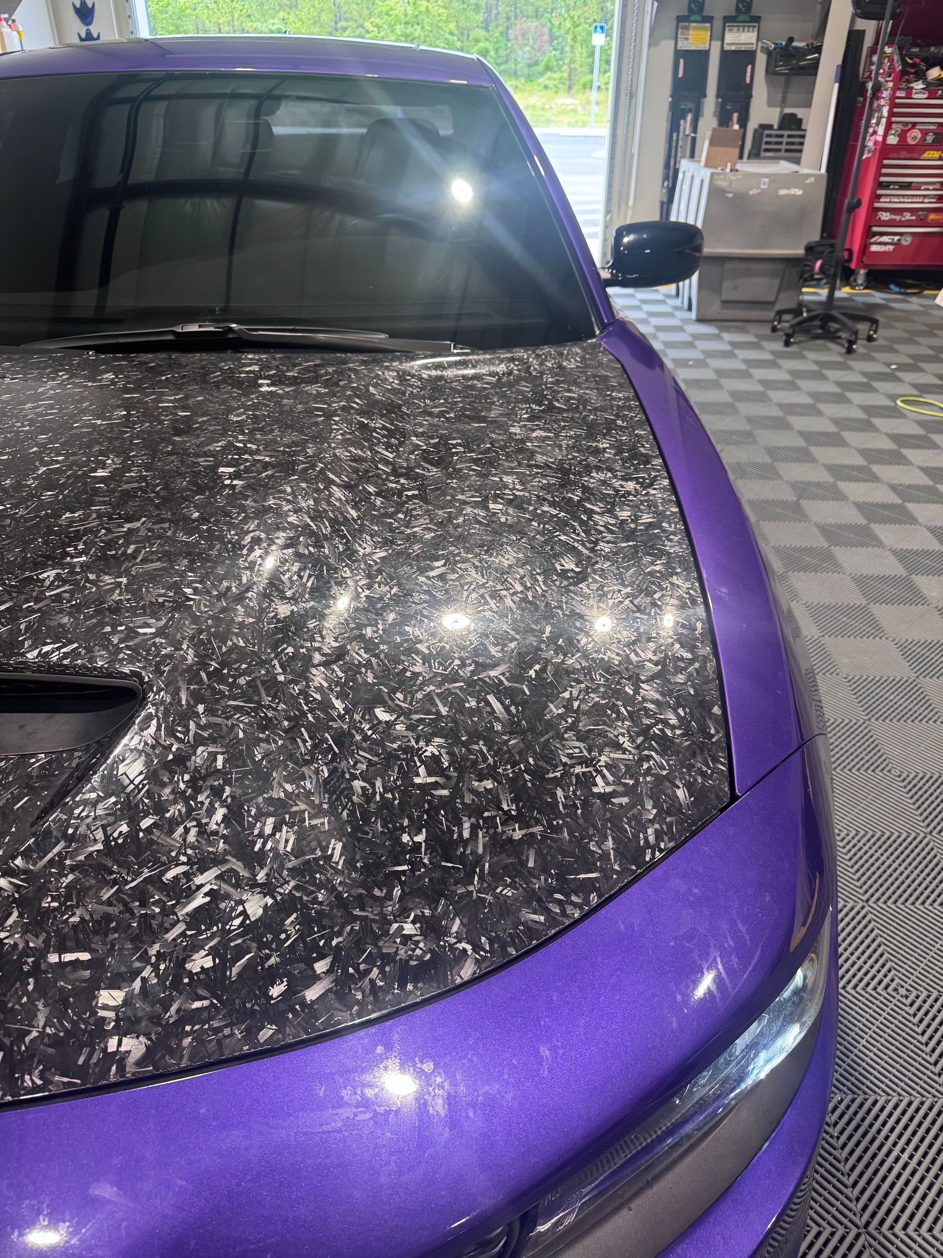 Purple car with carbon fiber hood in a garage.
