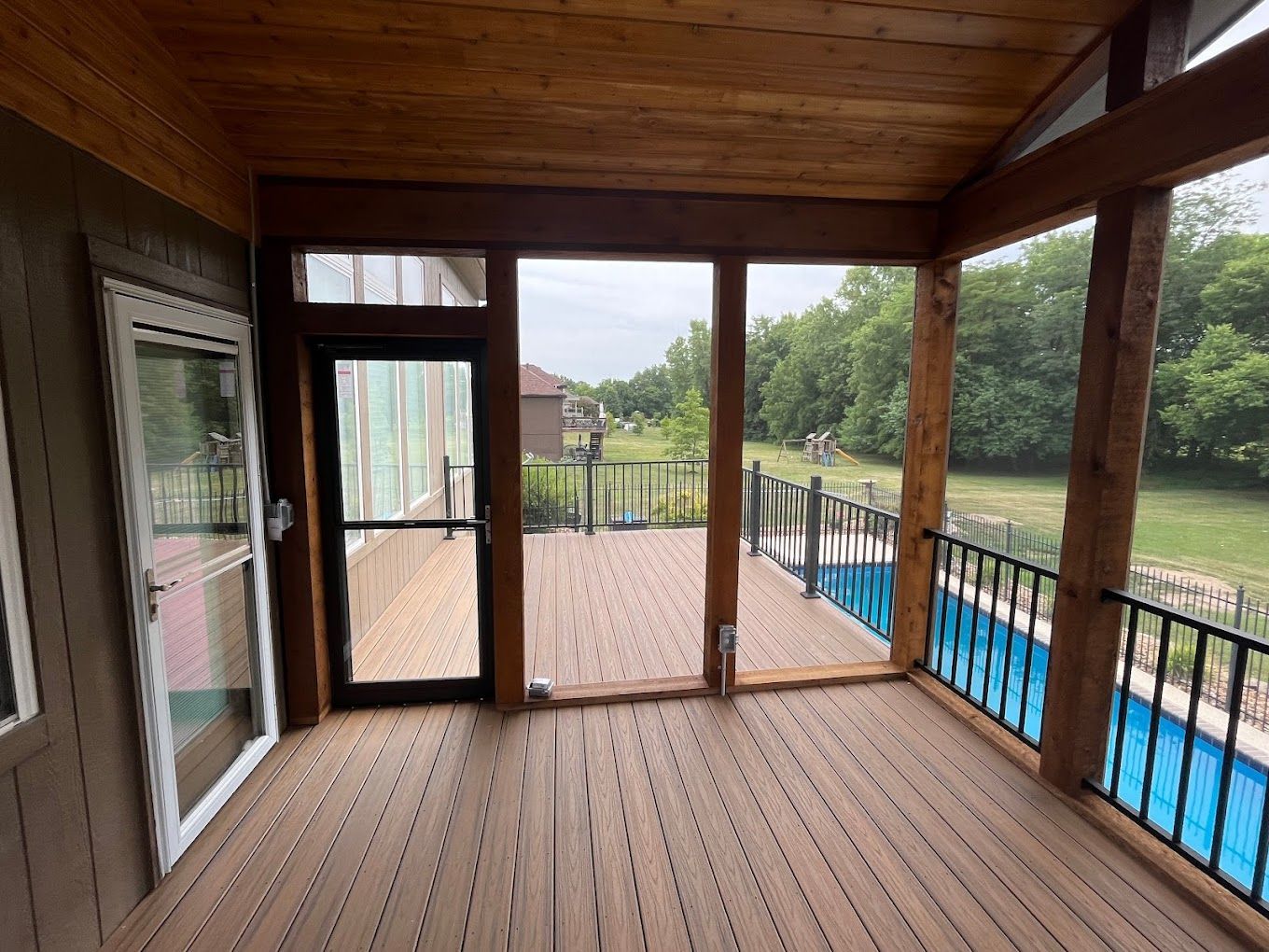 A screened in porch with a swimming pool in the background.