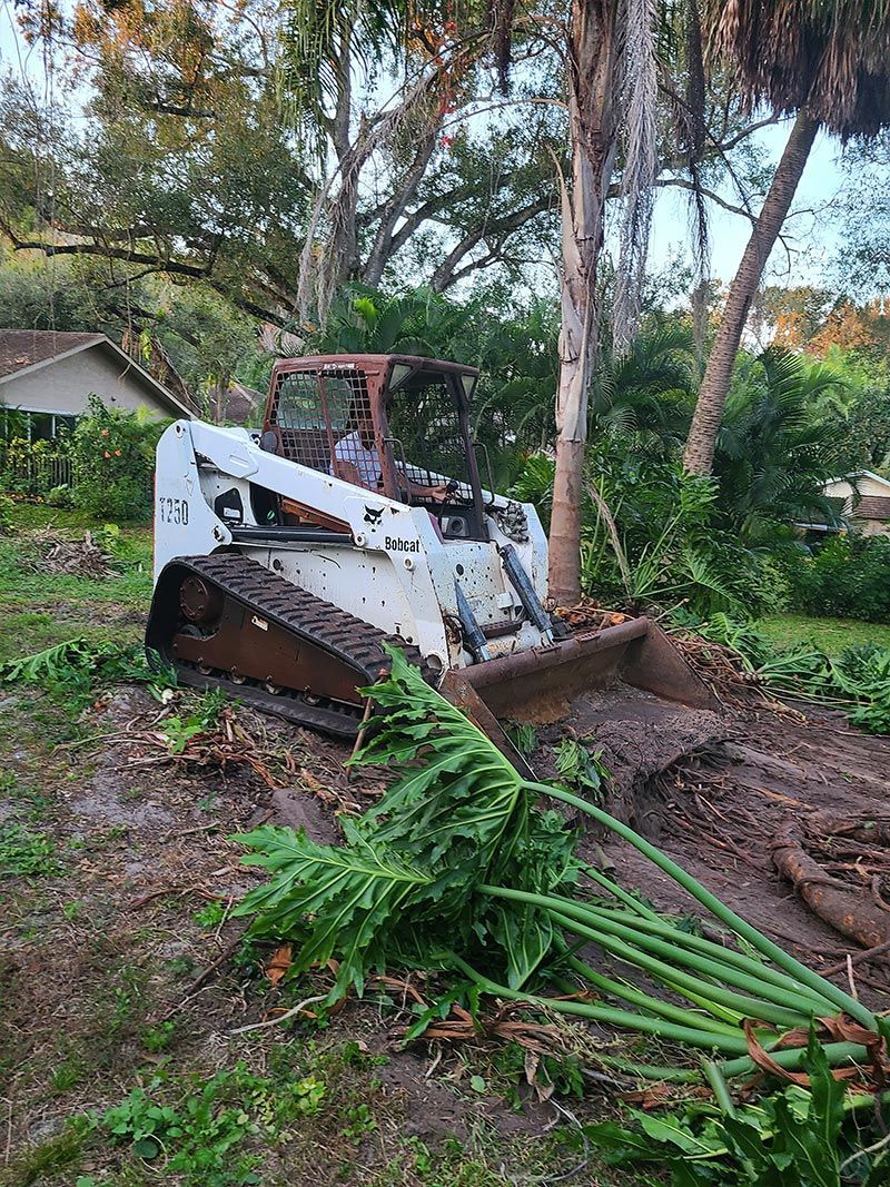 A bulldozer is cutting down a tree in a yard.