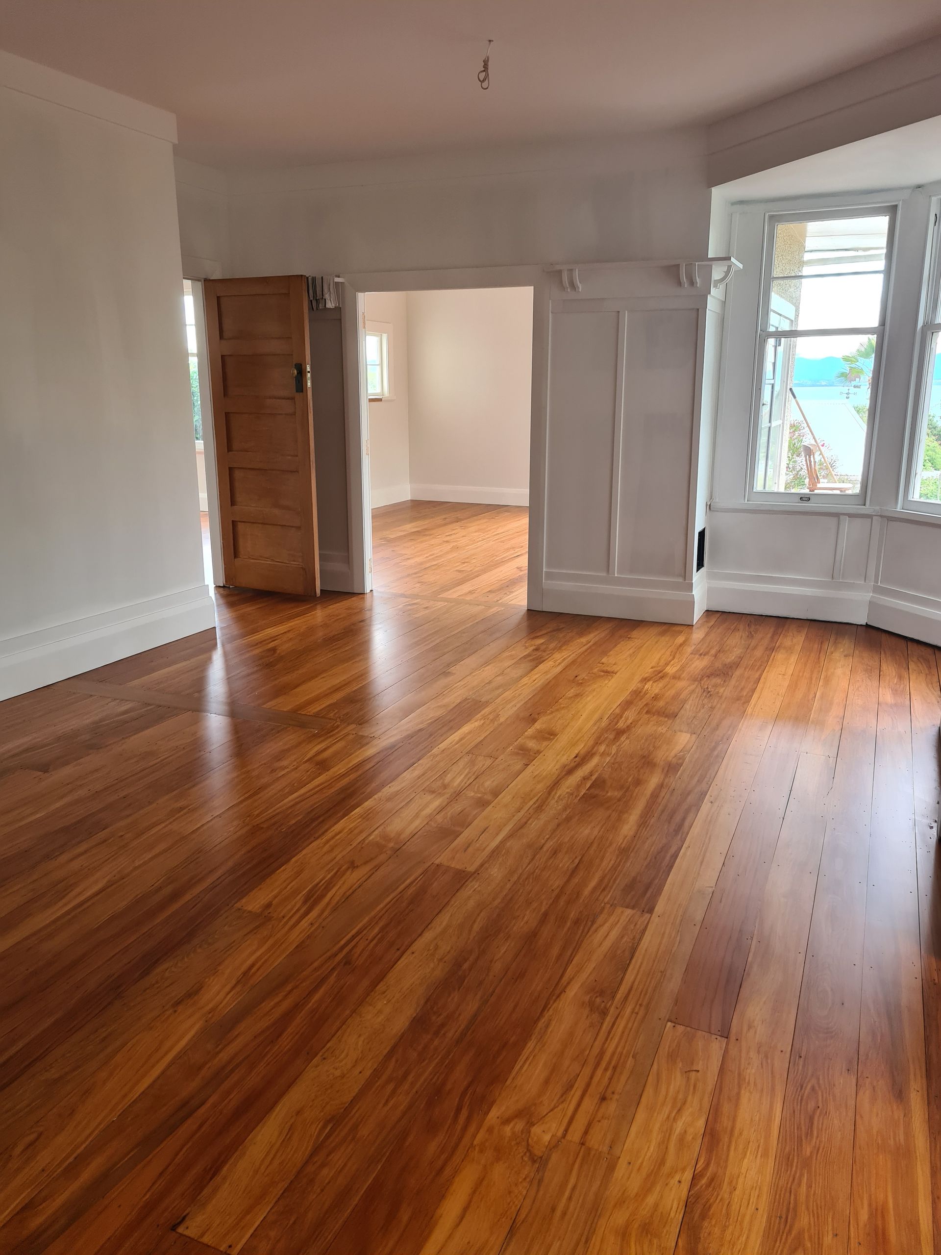 A large empty room with hardwood floors and white walls.