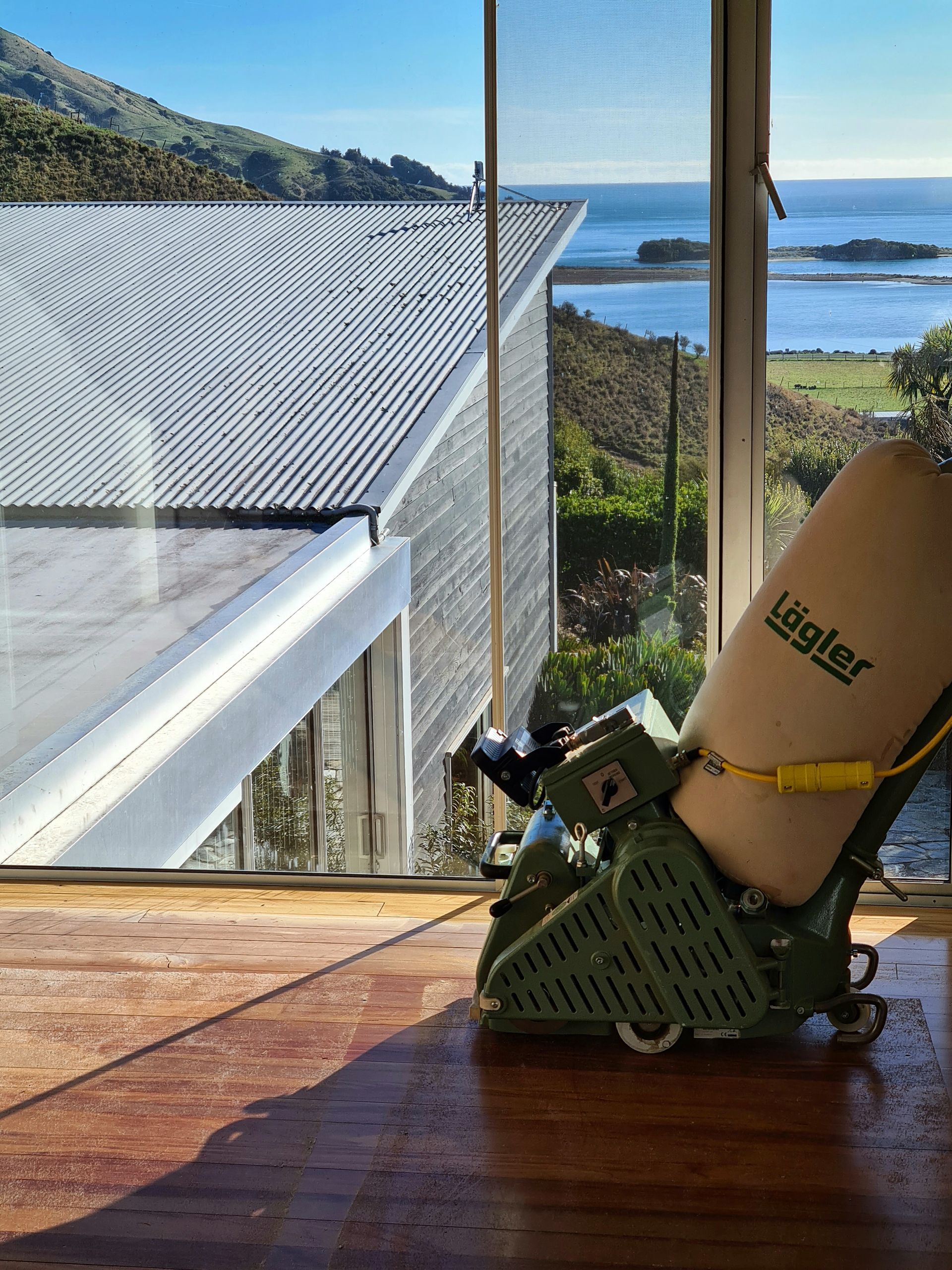 A leigher machine is sitting on a wooden floor in front of a window
