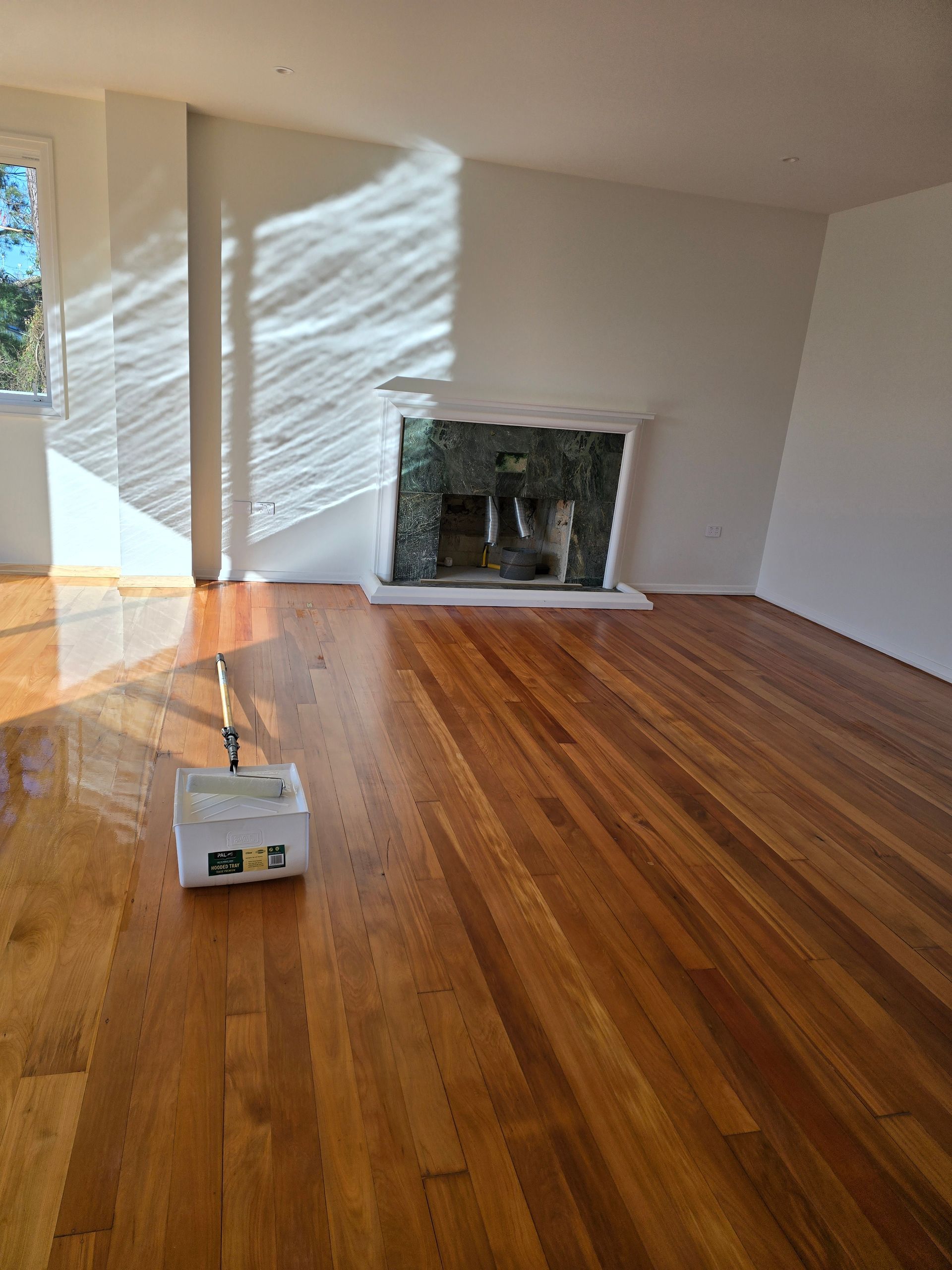 An empty living room with hardwood floors and a fireplace.