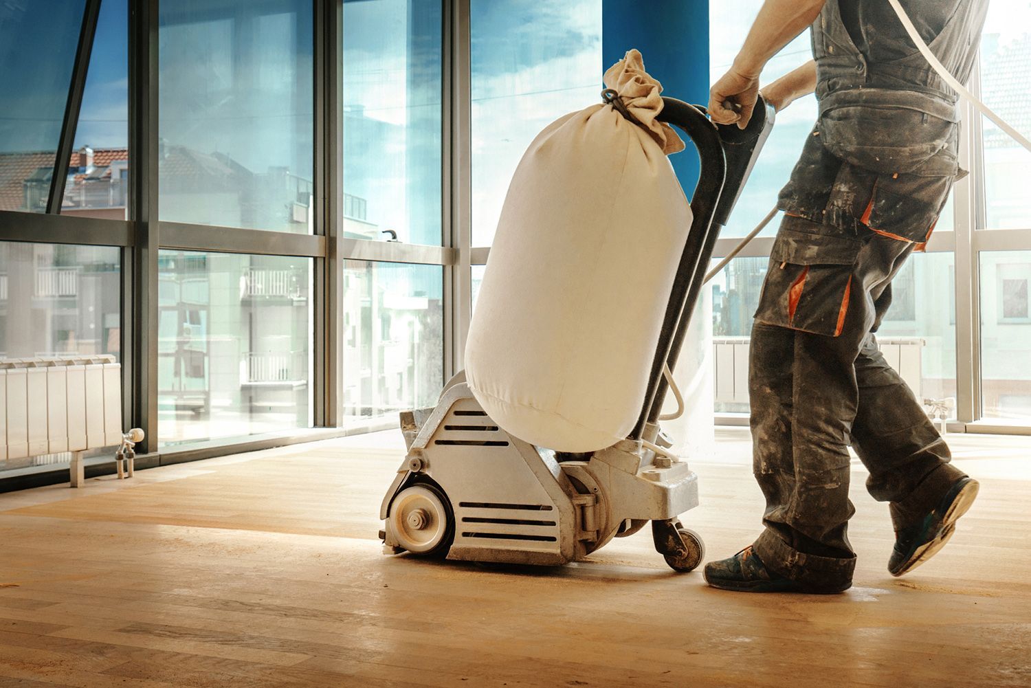 A man is sanding a wooden floor.