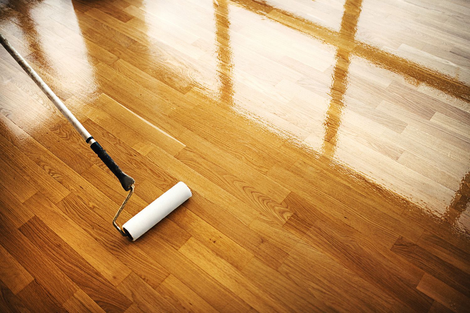 A roller is being used to polish a wooden floor.